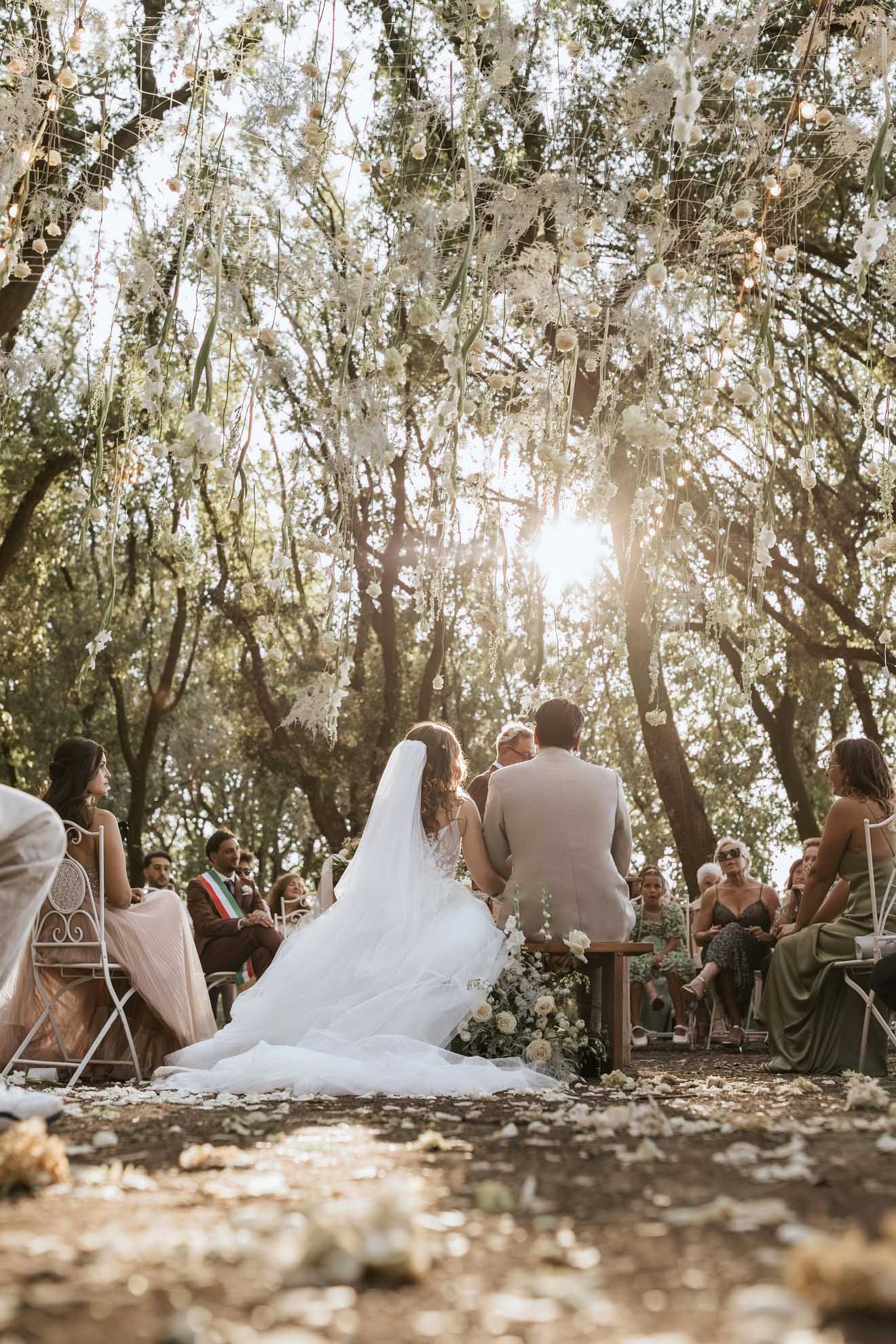 Simone, impeccabile nel suo abito sartoriale sabbia, e Chiara celebrano le loro promesse d’amore in un romantico allestimento floreale.